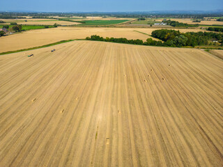 Fototapeta na wymiar High level aspect view over a wheat field with bales of straw ready for collection in the English countryside farmland