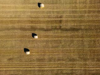 High level top down birds eye view aspect view over a wheat field with bales of straw ready for collection in the English countryside farmland © Dave