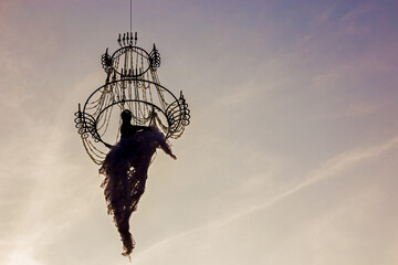 Air ballerina gymnast on a chandelier against the sky