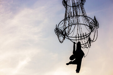 Air ballerina gymnast on a chandelier against the sky