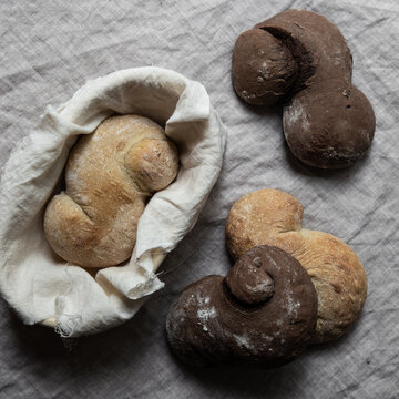 Plain and carob breads with bread basket on a linen tablecloth