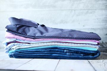 stack of men's shirts and jeans on table 