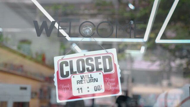 Asian young handsome barber salon owner or hairdresser turns open sign. Attractive male barber open sign on glass door prepare to welcome customer after covid-19 lockdown and quarantine at barbershop.