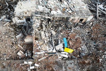 Top view of the destroyed building. Aerial view of ruins. wreckage of the building in the colors of the Ukrainian flag - Powered by Adobe