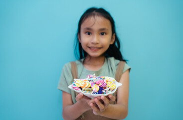 Child holding candy , jelly in hand Little asian girl eating candy.blow with colorful candies in the hands of little girl.