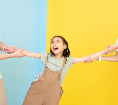 Unhappy Couple In Meeting And Argument,Divorce Concept.Asian Parents Fighting Over Their Child, Mad Man And Woman Quarrelling, Pulling Daughter's Hands In Different Directions, Standing In Living Room