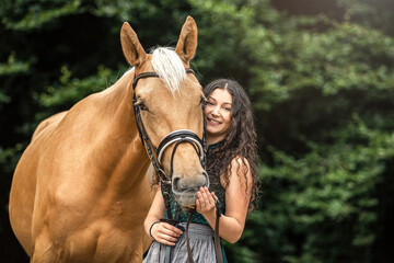 Equestrian and her horse team: Portrait of a young woman cuddle with her palomino kinsky warmblood...