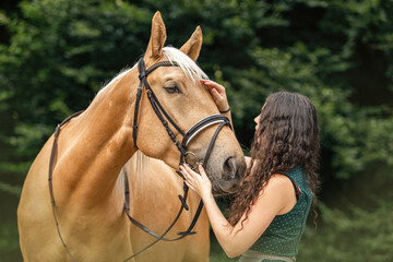 Equestrian and her horse team: Portrait of a young woman cuddle with her palomino kinsky warmblood...