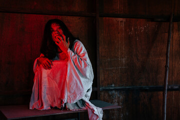 Asian woman dressed in white and put on a blood-stained face in a dark deserted area reflected by...