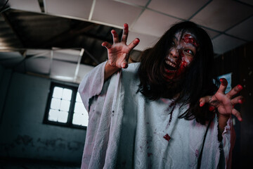 Woman dressed as a bloody white ghost in an abandoned house stares at the camera with an angry face.