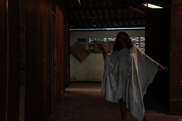 A female zombie in an abandoned house full of blood for Halloween.