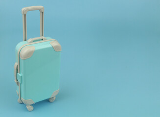 Blue travel suitcase on blue background with copy space for text. Vacation and travel concept.