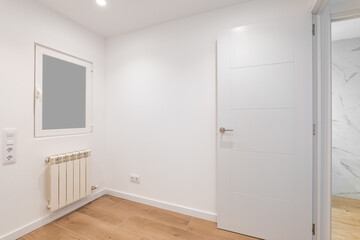 Empty room with frosted glass to avoid watching by neighbours. Laminate flooring and newly painted white walls in refurbished apartment.