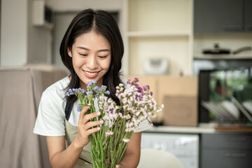 Weekend with her hobbies, Asian woman arranges a bouquet of flowers to decorate her home and...