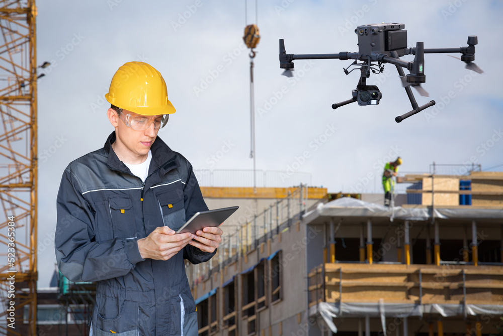 Poster engineer with digital tablet controls drone on a construction site