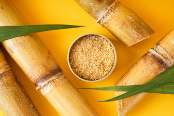 Brown sugar and sugar cane on a yellow background, closeup. Top view.