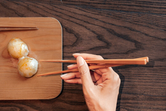 Close up of hand of woman eating asian food with chop sticks