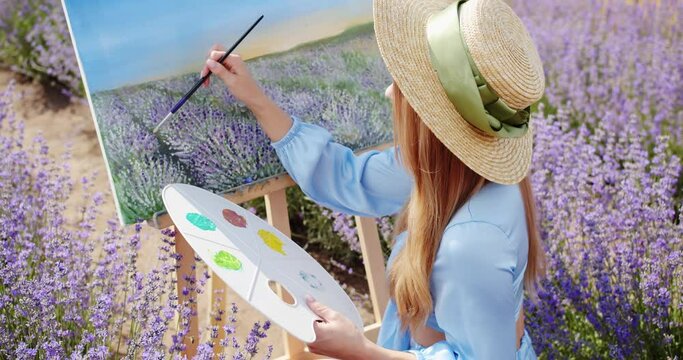a young artist paints a picture in a lavender field