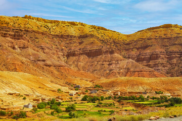 Beautiful moroccan atlas mointains valley landscape, secluded berber clay house at the foot of a steep rock face  - Gorges du Dades, Morocco