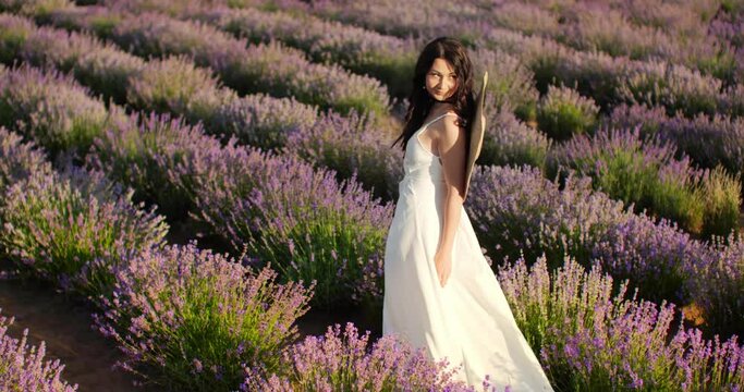 a girl in a white dress walks through a lavender field