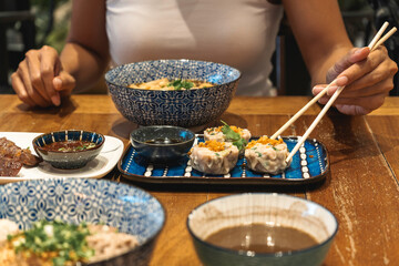 Close up of hand of woman eating asian food with chop sticks