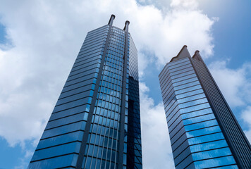 Fototapeta premium Modern tower buildings or skyscrapers in financial district with cloud on sunny day. bottom view
