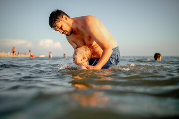 dad teaches young son to swim in the sea