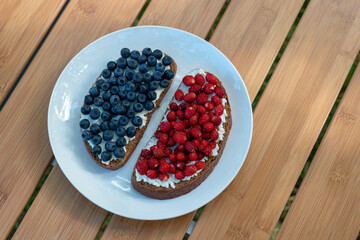 Sandwiches with wild berries collected in the forest. Blueberries and strawberries on cream cheese for breakfast. Summer concept.