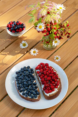 Sandwiches with wild berries collected in the forest. Blueberries and strawberries on cream cheese for breakfast. Summer concept.