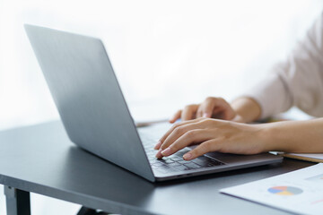 Close-up of a business woman typing a laptop computer on a desk in the office.