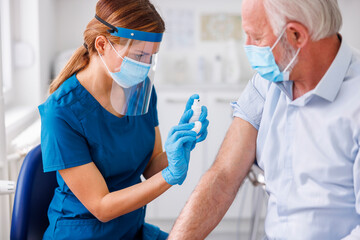 Healthcare specialist applying vaccine to elderly patient