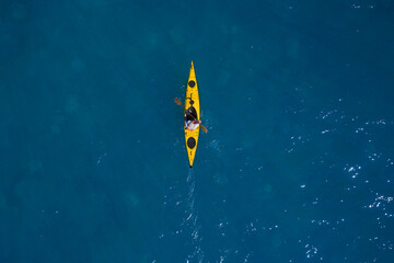 Yellow kayak In motion on blue water top view. Yellow canoe movement on water top view. - obrazy, fototapety, plakaty