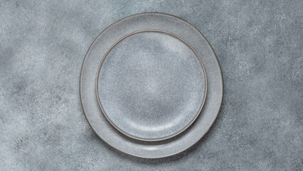 Empty gray plates on a gray stone background. Dishes for table setting. Top view, flat lay. Banner