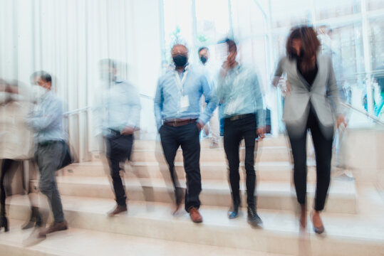 blurred businessmen and women descending the staircase