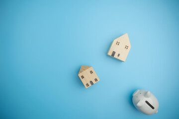 Concept savings, investment, save money in future copy space. Finance, loan, saving money concept. Top view of single white piggy bank with mini houses on blue background with copy space.