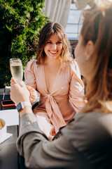 Two Women friends eating fresh oysters and drinking chilled prosecco wine on the summer sunset in restaurant. Seafood delicacies