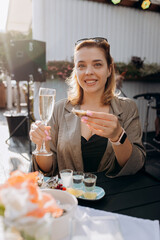 Beautiful Woman eating fresh oysters and drinking chilled prosecco wine on the summer sunset in restaurant. Seafood delicacies