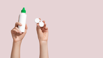 Woman holding contact lens case and solution on pink background