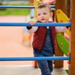 Fototapeta premium Sad toddler baby boy on the playground, unhappy child aged one year