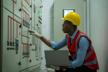 Engineer checking the electrical system with panel in control or server room.
