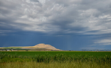 A hill on  a farm with dark stormy clouds, Cache Valley, Utah © Claire
