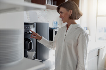 Business woman in casual clothes making a coffee in office kitchen during break. High quality photo