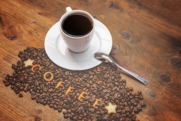 A cup of aromatic coffee and coffee beans on a wooden table.