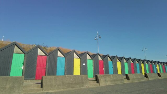 Panning shot of colourful beach huts on Lowestoft promenade on a bright and sunny morning