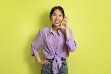 Happy Asian Woman Shouting Holding Hand Near Mouth, Yellow Background