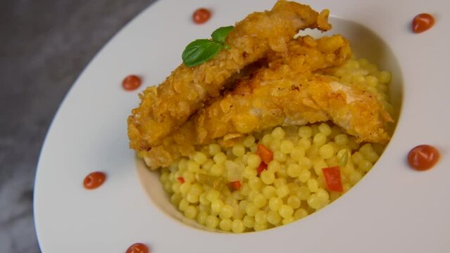 Recipe for chicken tenders with corn flakes and Italian Piombo pasta risotto and peppers on turntable. High quality video