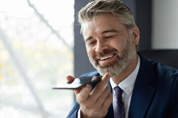 Handsome Middle Aged Businessman Recording Voice Message At Workplace In Office