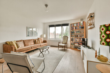 Comfortable couch located near carpet and table against window in spacious minimalist style living...