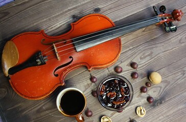 Fototapeta na wymiar Elegant breakfast still life with violin, cup of coffee, gooseberry and walnut jam on wooden background