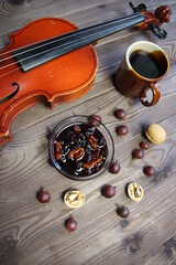 Elegant breakfast still life with violin, cup of coffee, gooseberry and walnut jam on wooden background